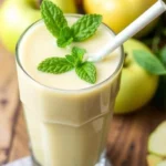 Creamy chilled custard apple smoothie shake garnished with fresh mint leaves in a glass