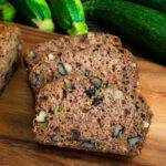Moist homemade cinnamon zucchini bread sliced on a rustic wooden board