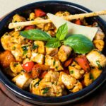 Juicy golden seared chicken breasts in a lemon herb garlic pan sauce with cherry tomatoes and spinach in a cast iron skillet