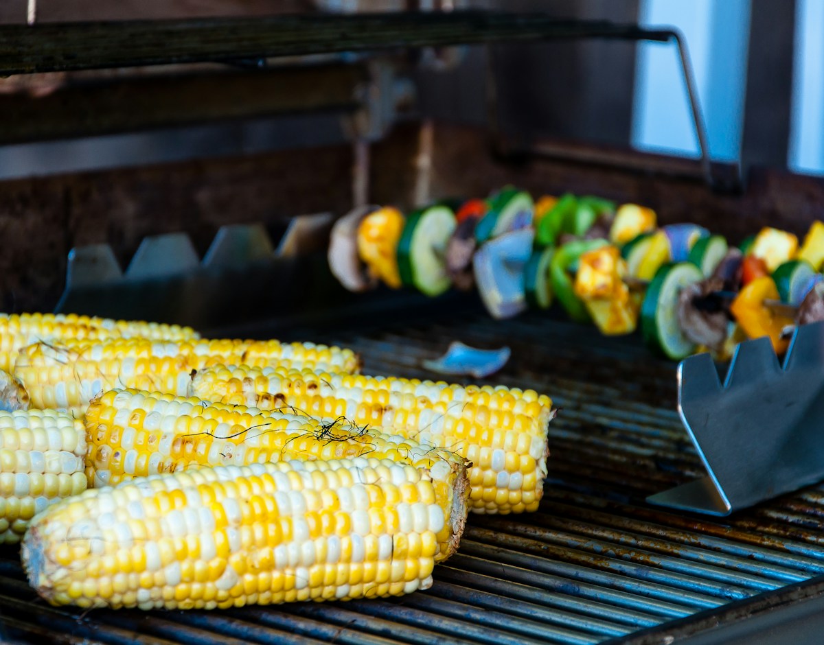Platter of steaming golden boiled and grilled corn on the cob slathered with melted butter, coarse sea salt, and black pepper