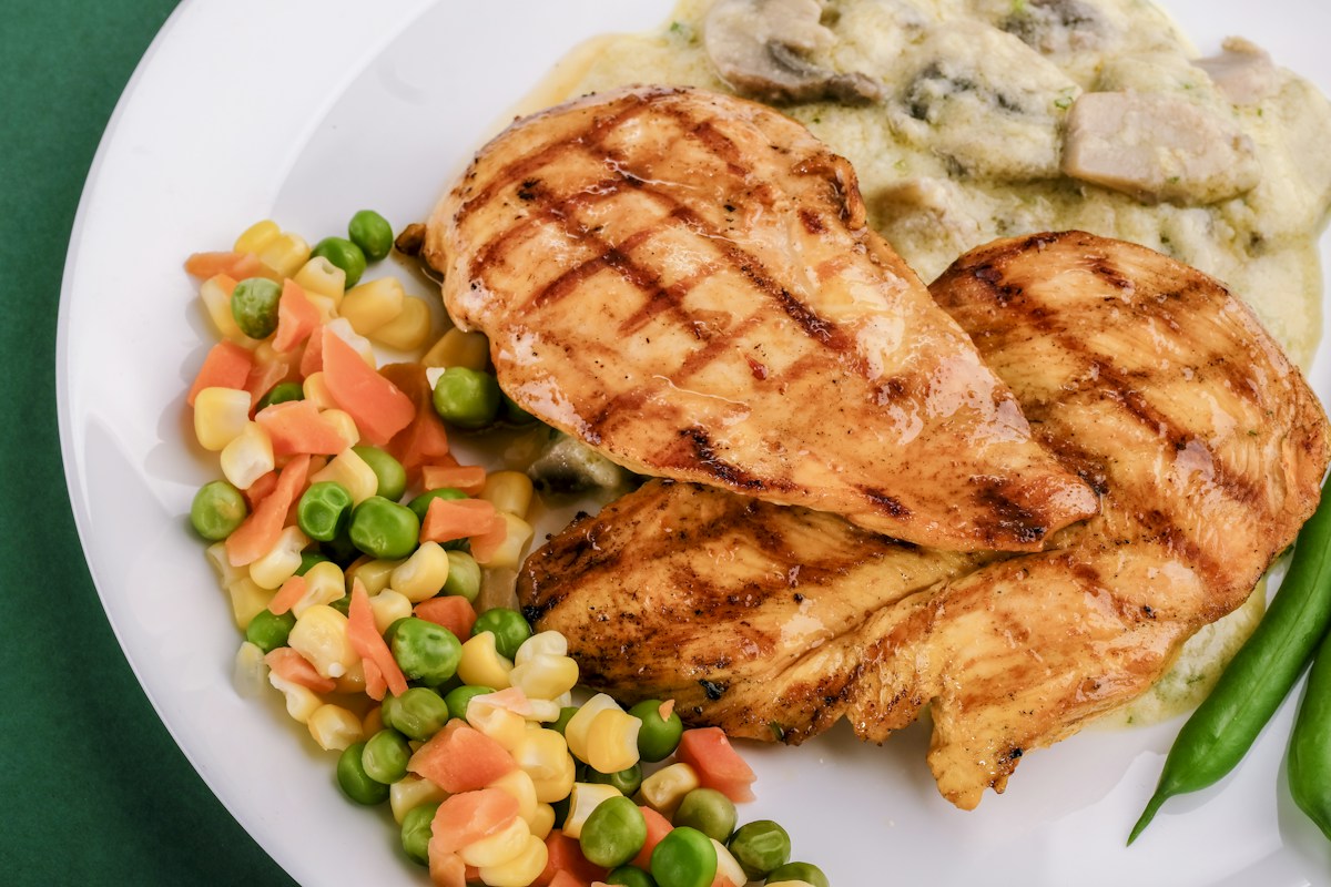 Golden-brown sliced juicy pan-seared chicken breast in a cast iron skillet garnished with garlic butter and rosemary